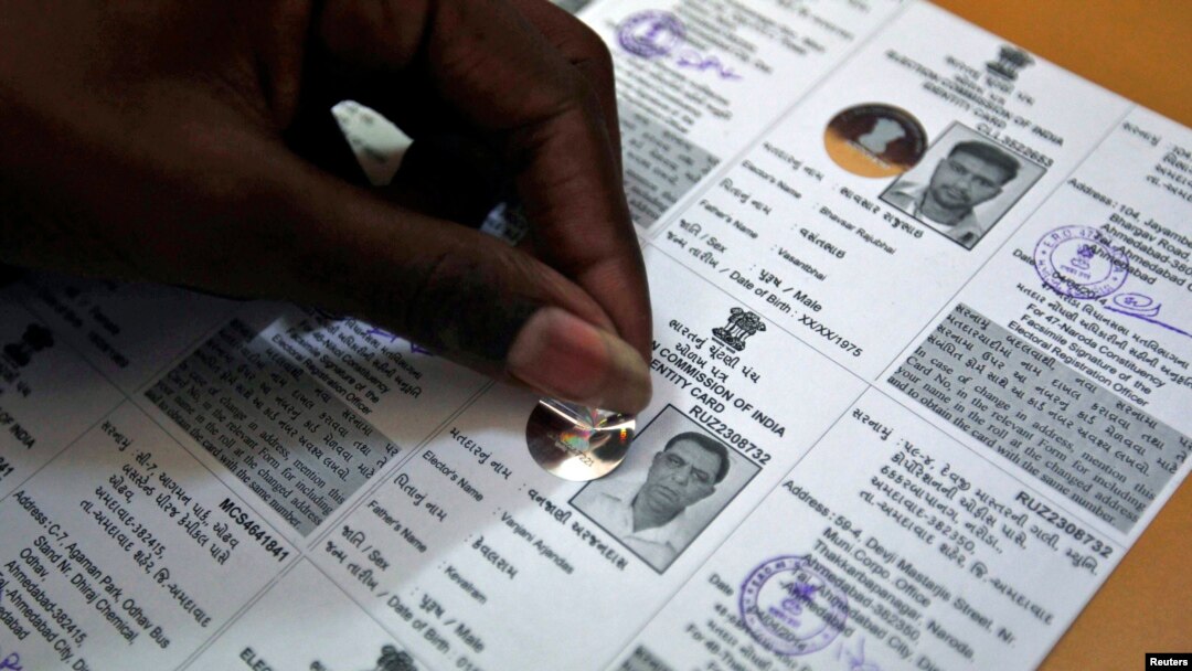 An election staff member pastes a hologram on a voter identification card at an election branch of a district administrative office in the western Indian city of Ahmedabad, April 4, 2014. 