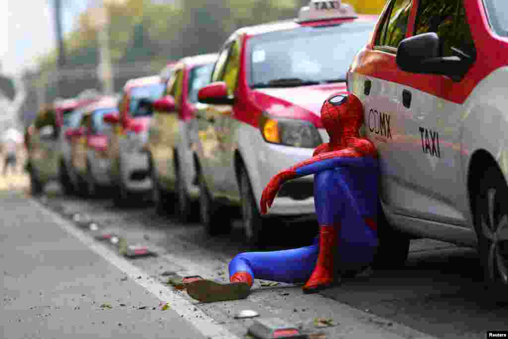 A person dressed up as Spider-Man sits next to a cab as taxi drivers hold a protest against taxi-hailing apps such as Uber, Cabify and Didi at Angel de la Independencia monument, in Mexico City, Oct. 12, 2020.