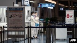 Anggota staf penerbangan berdiri di gerbang keberangkatan Bandara Internasional Haneda Tokyo pada 29 November 2021, ketika Jepang mengumumkan rencana untuk melarang semua pelancong asing baru atas varian omicron dari COVID-19. (Foto: AFP)