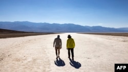 Los visitantes caminan bajo el sol en Badwater Basin en el Parque Nacional Death Valley, o Valle de la Muerte, cerca de Furnace Creek, durante una ola de calor que afectó al sur de California el 7 de julio de 2024. 