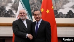 China's Foreign Minister Wang Yi shakes hands with Iran's Foreign Minister Mohammad Javad Zarif during a meeting at the Diaoyutai state guest house in Beijing, Dec. 31, 2019.