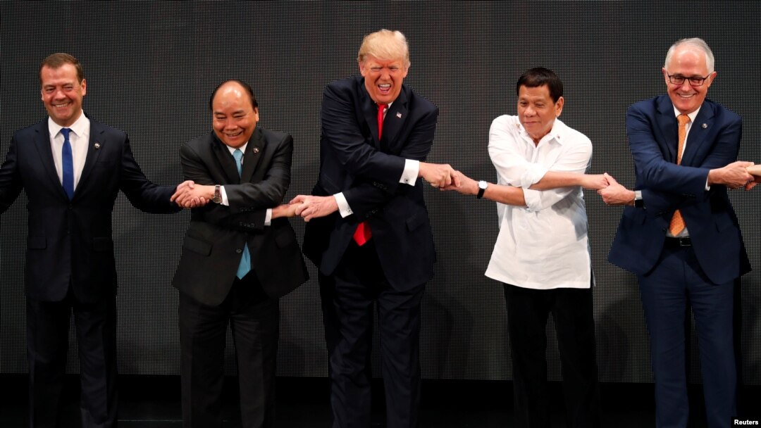Presiden Donald Trump tersenyum bersama pemimpin lain, termasuk Perdana Menteri Rusia Dmitry Medvedev, Perdana Menteri Vietnam Nguyen Xuan Phuc, Presiden Filipina Rodrigo Duterte dan Perdana Menteri Australia Malcolm Turnbull melakukan jabat tangan khas ASEAN pada KTT ASEAN di Manila, Filipina, 13 November 2017. 