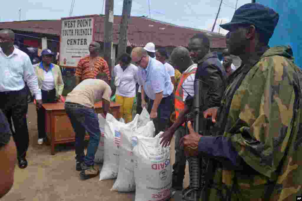 People hand out foodstuff donated by the U.S at the West Point area that has been hard hit by the Ebola virus in Monrovia, Liberia, Aug. 26, 2014.