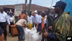 People hand out foodstuff donated by the U.S at the West Point area that has been hard hit by the Ebola virus in Monrovia, Liberia, Aug. 26, 2014.