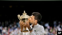 Petenis asal Serbia, Novak Djokovic, mencium piala kemenangan setelah mengalahkan petenis Swiss, Roger Federer, dalam final nomor tunggal putra turnamen Wimbledon di London, 14 Juli 2019.