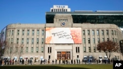 24일 한국 서울시청 앞에 설치된 임시 신종 코로나바이러스 감염 검사소에서 검사를 받기 위해 줄 선 사람들.