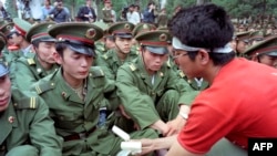 资料照：绝食学生向守在人民大会堂外的解放军士兵送冰棒。(1989年5月15日)