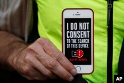 FILE - A man holds up his iPhone during a rally in support of data privacy outside an Apple store in San Francisco, Calif., Feb. 23, 2016. Protesters lashed out at a government order requiring Apple to help unlock an encrypted iPhone.