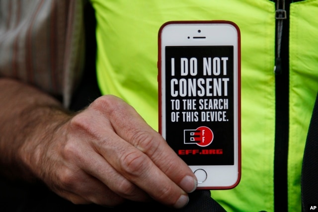 FILE - A man holds up his iPhone during a rally in support of data privacy outside an Apple store in San Francisco, Calif., Feb. 23, 2016. Protesters lashed out at a government order requiring Apple to help unlock an encrypted iPhone.