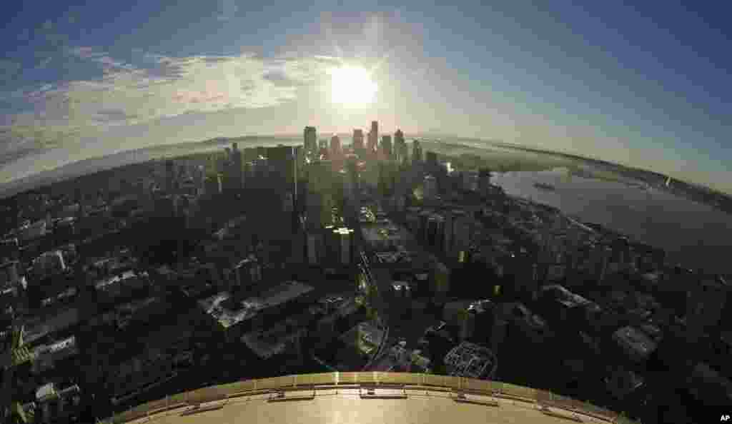 In this image taken with a fisheye lens, he sun rises over downtown Seattle on a misty morning as viewed from the roof of the Space Needle.