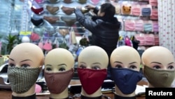 FILE - A vendor arranges a shelf full of masks as he waits for customers in a shopping mall in Yiwu, Zhejiang province, China.