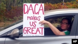 An unidentified woman holds a sign as she drives through rush hour traffic in Portland, Ore., Sept. 5, 2017. President Donald Trump Tuesday began dismantling the Deferred Action for Childhood Arrivals, or DACA, program, the government program protecting