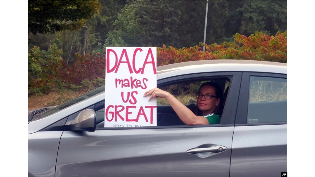 FILE - An unidentified woman holds a sign as she drives through rush-hour traffic in Portland, Ore., Sept. 5, 2017.