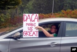 An unidentified woman holds a sign as she drives through rush hour traffic in Portland, Ore., Sept. 5, 2017.
