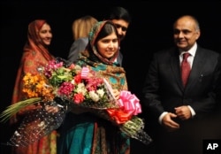 FILE - Malala Yousafzai holds flowers after speaking during a media conference at the Library of Birmingham, in Birmingham, England, Oct. 10, 2014, after she was named as winner of The Nobel Peace Prize.