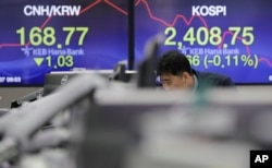 A man watches computer monitors near the screens showing the Korea Composite Stock Price Index (KOSPI), right, and the foreign exchange rate at the foreign exchange dealing room in Seoul, South Korea.