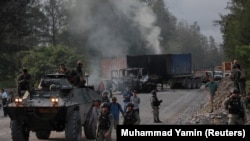 Polisi dan pasukan keamanan terlihat di dekat kendaraan yang dibakar oleh para pekerja perusahaan pertambangan raksasa A.S. Freeport McMoran Inc selama perselisihan perburuhan di Timika, Papua, 19 Agustus 2017. (Foto: REUTERS/Muhammad Yamin)
