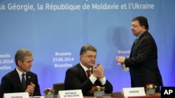 From left, Moldova's Prime Minister Lurie Leanca, Ukrainian President Petro Poroshenko and European Commission President Jose Manuel Barroso participate in a signing ceremony at an EU summit in Brussels on Friday, June 27, 2014.