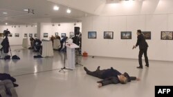 Andrei Karlov (2ndR), the Russian ambassador to Ankara, lies on the floor after being shot by a gunman (R) during an attack at a public event in Ankara, Turkey, Dec. 19, 2016.