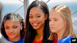 U.S. gymnastics team member Gabby Douglas is flanked by teammates Laurie Hernandez, left, and Madison Kocian, during a visit to the Empire State Building in New York, Aug. 23, 2016.