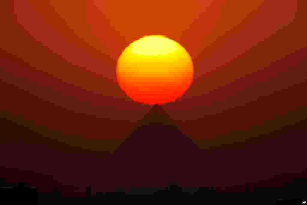 The sun sets over the the Giza Pyramids, near Cairo, Egypt.