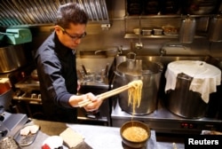 FILE - Kenji Saito cooks at his ramen noodle shop in Tokyo, Japan, April 12, 2019.