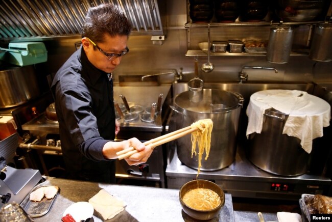 FILE - Kenji Saito cooks at his ramen noodle shop in Tokyo, Japan, April 12, 2019.