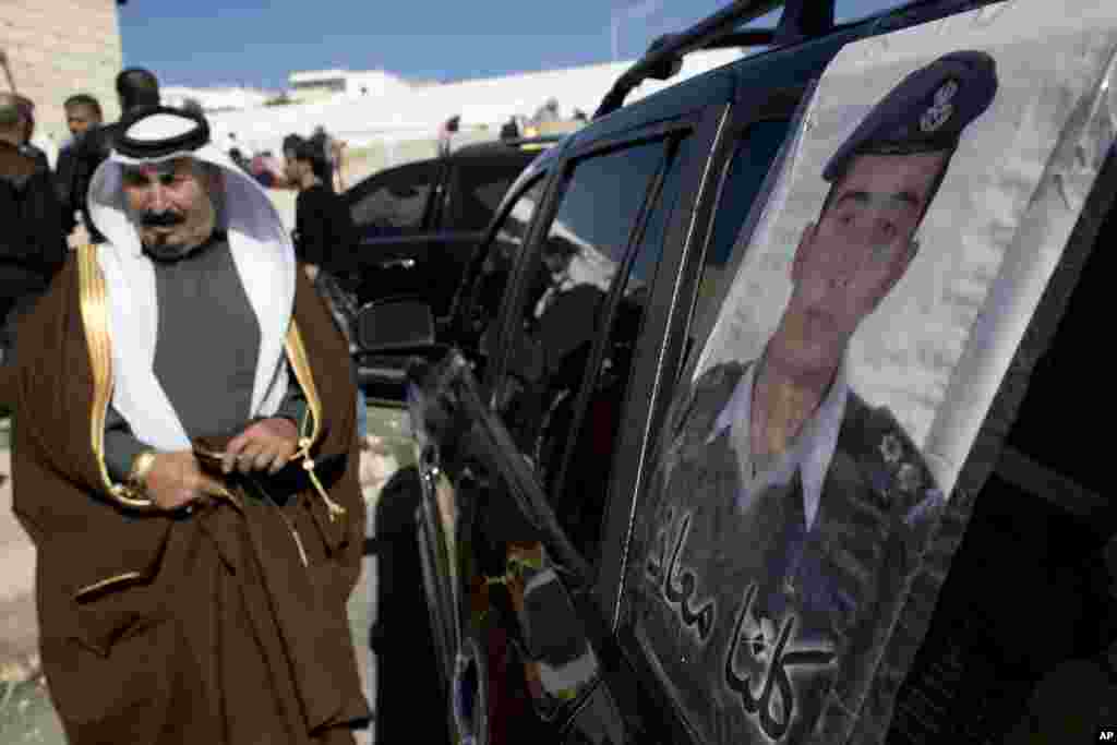 Một người đàn ông Jordan đi qua một tấm áp phích dán trên một chiếc xe với hình ảnh của phi công bị giết, Trung tá Muath al-Kaseasbeh, với hàng chữ tiếng Ả Rập &#39;Tất cả chúng tôi là Muath&#39; tại quê nhà của al-Kaseasbeh gần Karak, ngày 4/2/2015.