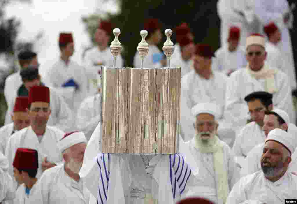 A member of the Samaritan sect holds a Torah scroll during their traditional pilgrimage marking the holiday of Shavuot, atop Mount Gerizim near the West Bank city of Nablus. The Samaritans, who trace their roots to the biblical Kingdom of Israel in what is now the northern occupied West Bank, observe religious practices similar to those of Judaism.