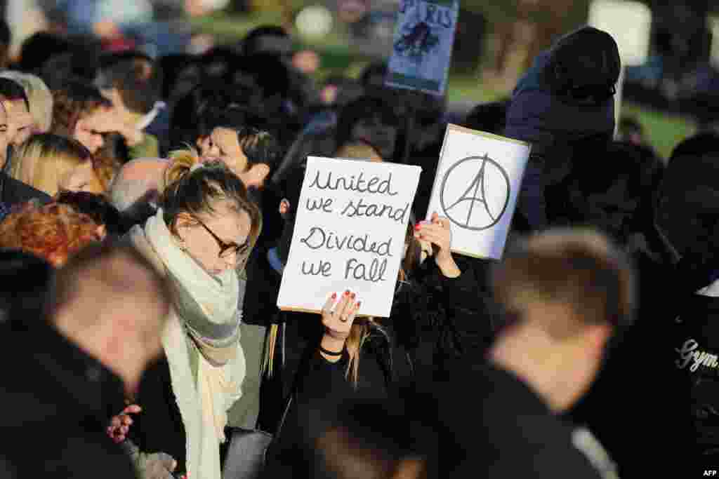 A woman holds the &quot;#PeaceForParis&quot; logo and a sign reading &quot;United we stand, Divided we fall&quot; on Nov. 15, 2015 in Caen during a demonstration in front of the Memorial of Caen in tribute to the victims of the Paris attacks.