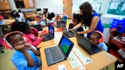 Second grade student Khalil Morgan, left, reacts after completing an interactive math problem on his computer, with teacher Jillian Martin, standing to the right, at Turner Elementary School in southeast Washington, Tuesday, Aug. 29, 2017. (AP Photo/Manue