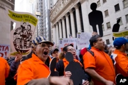 抗议者游行走过纽约股票交易所外的华尔街。（2018年5月1日）