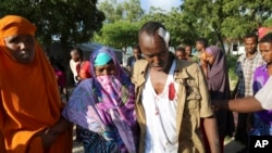 Mpigaji picha wa Reuters Feisal Omar, kati, alijeruhiwa na mlipuko wa bomu akiwa na jamaa zake nje ya hospitali ya Medina Hospital Mogadishu, Somalia, Nov. 1, 2015. 