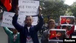 FILE - Protesters hold marked images of Chinese President Xi Jinping and anti-China signs during a protest ahead of his recent visit to Vietnam, on the street in Hanoi, Nov. 3, 2015.