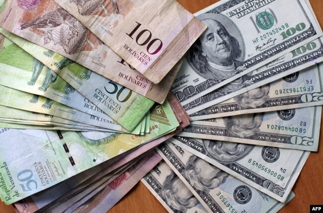 FILE - U.S. dollars and Venezuelan Bolivares "fuertes" bills are seen in Caracas, Aug. 17, 2009.