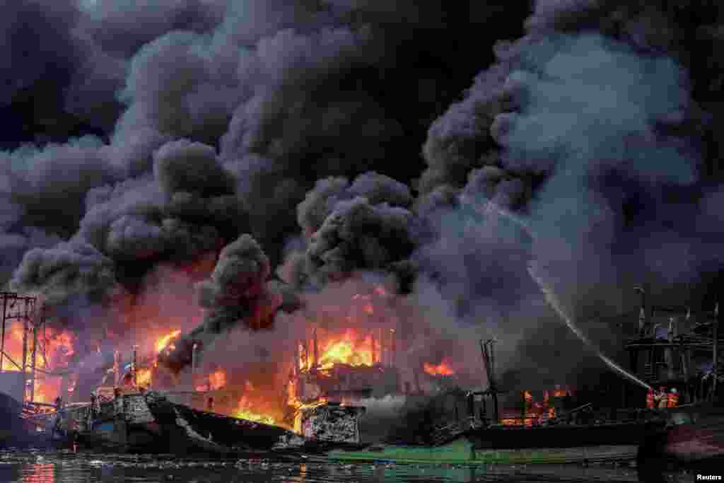Firefighters extinguish the fire burning fishing boats at Muara Baru port in Jakarta, Indonesia, Feb. 23, 2019, in this photo taken by Antara Foto.