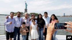 Luis Mendez Chanes, third left, poses with his daughter Marta Mendez, fourth left, as they reunite after 24 years in front of the Statue of Liberty aboard the Bateaux New York boat, July 5, 2017, in New York.