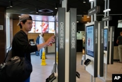 Brandon Alba from Milwaukee orders food at a self-service kiosk at a McDonald's restaurant in Chicago, June 1, 2017. The company that helped define fast food is making supersized efforts to reverse its fading popularity and catch up to a landscape that has evolved around it.