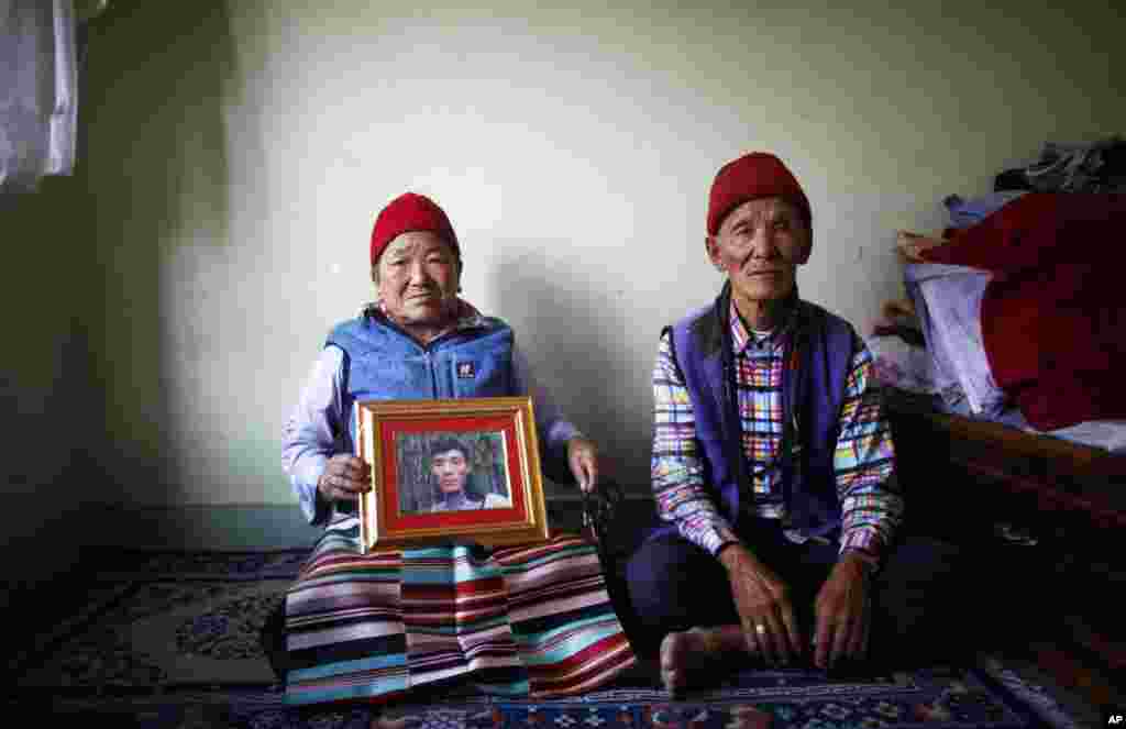 Nimdige Sherpa memegang foto putranya Ang Kaji Sherpa yang tewas dalam salju longsor di Gunung Everest, bersama suaminya Ankchu Sherpa di dalam apartemen mereka di Katmandu, Nepal (23/4). (AP/Niranjan Shrestha)