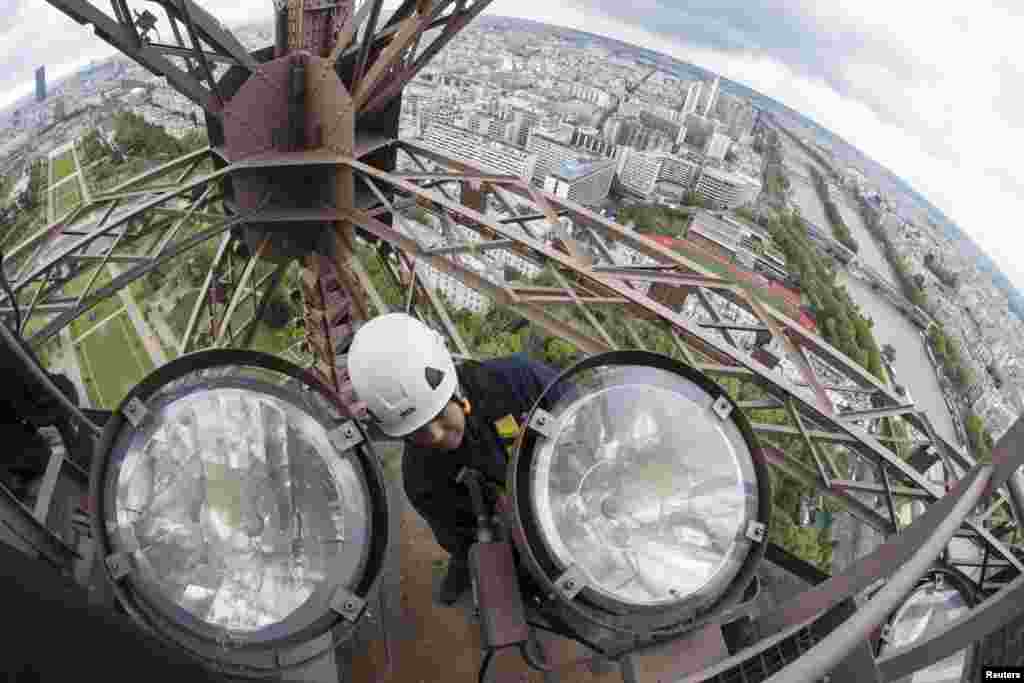 Technician Pascal Duteil changes one of the sodium golden light bulbs on the Eiffel tower in Paris. The task to change and clean the 425 golden light bulbs starts today and is done every four years.