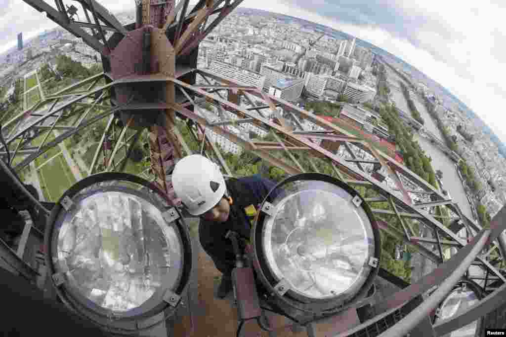 Teknisi Pascal Duteil mengganti salah satu bohlam sodium emas di menara Eiffel di Paris. Tugas untuk mengganti dan membersihkan 425 bohlam emas mulai hari ini dan dilakukan setiap empat tahun sekali.