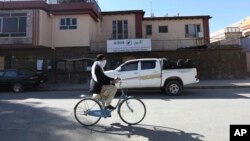 FILE - An Afghan man rides his bicycle in front of the office of the Agency Coordinating Body for Afghan Relief (ACBAR) in Kabul, Afghanistan, Nov. 6, 2016. Criminal gangs in Afghanistan often kidnap foreign aid workers, sometimes selling them to insurgents.