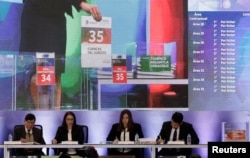 An employee of Mexico's National Hydrocarbons Commission is seen on a screen as she places documents during an auction of shallow-water oil and gas blocks, in Mexico City, March 27, 2018.