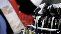 Egyptian anti-riot police stand by a national flag as the trial of former President Hosni Mubarak resumes at the Police Academy on the outskirts of Cairo, December 28, 2011.