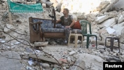 A Free Syrian Army fighter sits on a sofa along a street in Aleppo's Salaheddine neighbourhood July 30, 2013. 