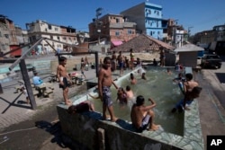 FILE - Children play in a pool that has no system to replace the water in Rio de Janeiro, Brazil, Aug. 13, 2015. Brazil is among the world’s largest economies, but lags in access to water and sanitation. Rapid urban growth in recent decades, poor planning, political infighting and economic instability are largely to blame, experts say.