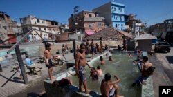 FILE - Children play in a pool that has no system to replace the water in Rio de Janeiro, Brazil, Aug. 13, 2015. Brazil is among the world’s largest economies, but lags in access to water and sanitation. Rapid urban growth in recent decades, poor planning