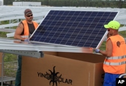 FILE - Workers install solar panels at the Constantine photovoltaic power station in Cestas, near Bordeaux, southwestern France.