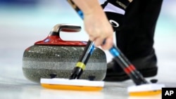 FILE - Members of Scotland's team sweep a path for the stone during their match against Sweden in the CPT World Women's Curling Championship 2017 in Beijing, China, March 25, 2017. 