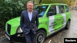 FILE - Australian mining billionaire Andrew Forrest poses in front of a taxi promoting green hydrogen clean energy alternatives, in London, Britain, Oct. 25, 2021.